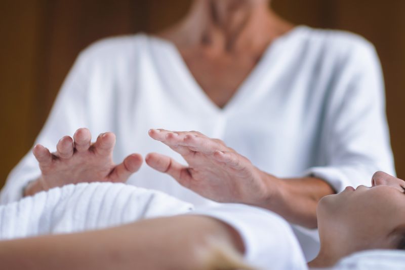 reiki Therapist hands hovering over relaxed client